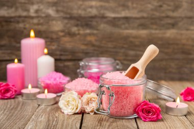 Banyo için deniz tuzu aromalı ve ahşap kaplamalı gül çiçekli. Pembe deniz tuzu. Spa tedavileri. Doğal tuz, bitkiler ve gerekli yağlar. Cilt bakımı. Mesaj için Meso. Boşluğu kopyala