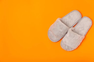Açık renkli arka planda yumuşak terlikler, yakın plan. Ev terlikleri. Ev için rahat ayakkabılar. Ayak bakımı konsepti. Ev rahatlığı. Mesaj için yer var. Boşluğu kopyala.