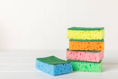 Arka planda renkli bulaşık süngerleri. Mutfak süngeri. Temizlik konsepti, temizlik hizmeti. Bulaşık deterjanı ve temiz ve kirli tabaklar. Metin için yer, kopyalama alanı. Bulaşıkları yıka..