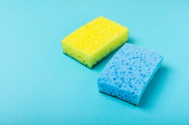 Arka planda renkli bulaşık süngerleri. Mutfak süngeri. Temizlik konsepti, temizlik hizmeti. Bulaşık deterjanı ve temiz ve kirli tabaklar. Metin için yer, kopyalama alanı. Bulaşıkları yıka..