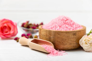 Banyo için deniz tuzu aromalı ve ahşap kaplamalı gül çiçekli. Pembe deniz tuzu. Spa tedavileri. Doğal tuz, bitkiler ve gerekli yağlar. Cilt bakımı. Mesaj için Meso. Boşluğu kopyala