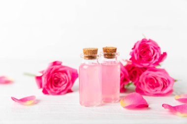 Arka planda gül yağı. Güller ve bir şişe parfümlü su. Romaterapi tedavisi. Güzellik konsepti. Spa prosedürü. Doğal organik yağ. Stres önleyici, detoks gevşetici.