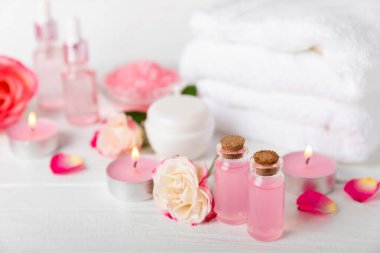 Arka planda gül yağı. Güller ve bir şişe parfümlü su. Romaterapi tedavisi. Güzellik konsepti. Spa prosedürü. Doğal organik yağ. Stres önleyici, detoks gevşetici.