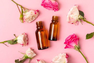 Arka planda gül yağı. Güller ve bir şişe parfümlü su. Romaterapi tedavisi. Güzellik konsepti. Spa prosedürü. Doğal organik yağ. Stres önleyici, detoks gevşetici.