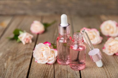 Arka planda gül yağı. Güller ve bir şişe parfümlü su. Romaterapi tedavisi. Güzellik konsepti. Spa prosedürü. Doğal organik yağ. Stres önleyici, detoks gevşetici.