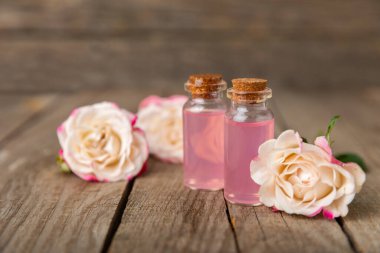Arka planda gül yağı. Güller ve bir şişe parfümlü su. Romaterapi tedavisi. Güzellik konsepti. Spa prosedürü. Doğal organik yağ. Stres önleyici, detoks gevşetici.