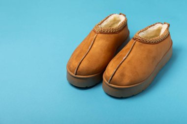 Açık renkli arka planda yumuşak terlikler, yakın plan. Ev terlikleri. Ev için rahat ayakkabılar. Ayak bakımı konsepti. Ev rahatlığı. Mesaj için yer var. Boşluğu kopyala.