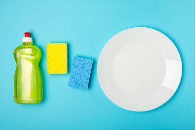 Arka planda renkli bulaşık süngerleri. Mutfak süngeri. Temizlik konsepti, temizlik hizmeti. Bulaşık deterjanı ve temiz ve kirli tabaklar. Metin için yer, kopyalama alanı. Bulaşıkları yıka..