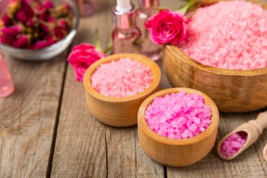 Banyo için deniz tuzu aromalı ve ahşap kaplamalı gül çiçekli. Pembe deniz tuzu. Spa tedavileri. Doğal tuz, bitkiler ve gerekli yağlar. Cilt bakımı. Mesaj için Meso. Boşluğu kopyala