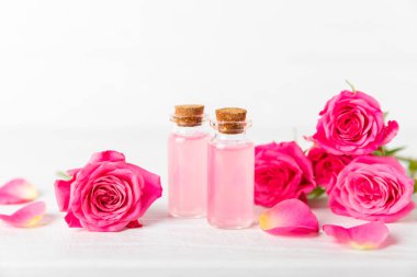 Arka planda gül yağı. Güller ve bir şişe parfümlü su. Romaterapi tedavisi. Güzellik konsepti. Spa prosedürü. Doğal organik yağ. Stres önleyici, detoks gevşetici.