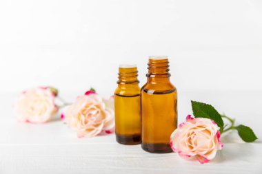 Arka planda gül yağı. Güller ve bir şişe parfümlü su. Romaterapi tedavisi. Güzellik konsepti. Spa prosedürü. Doğal organik yağ. Stres önleyici, detoks gevşetici.