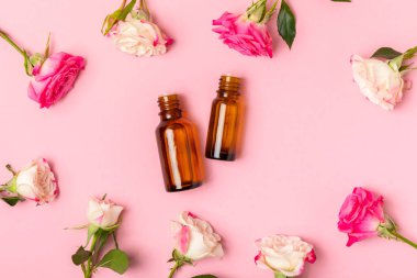 Arka planda gül yağı. Güller ve bir şişe parfümlü su. Romaterapi tedavisi. Güzellik konsepti. Spa prosedürü. Doğal organik yağ. Stres önleyici, detoks gevşetici.