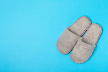 Açık renkli arka planda yumuşak terlikler, yakın plan. Ev terlikleri. Ev için rahat ayakkabılar. Ayak bakımı konsepti. Ev rahatlığı. Mesaj için yer var. Boşluğu kopyala.