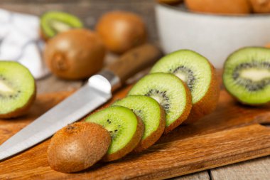 Ahşap arka planda Kivi. Masada tam meyve ve dilimler halinde yeşil kivi var. Taze sulu kivi. Tropik meyve. Organik meyve. Sağlıklı beslenme. Mesaj için yer var. Boşluğu kopyala.