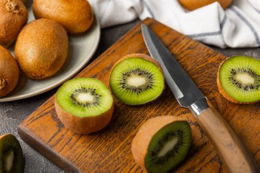 Ahşap arka planda Kivi. Masada tam meyve ve dilimler halinde yeşil kivi var. Taze sulu kivi. Tropik meyve. Organik meyve. Sağlıklı beslenme. Mesaj için yer var. Boşluğu kopyala.