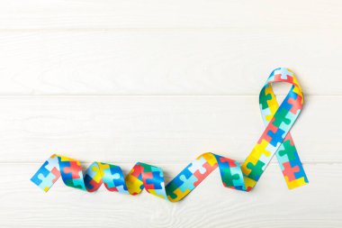 Otizm kurdelesi. Otizm farkındalık günü. Yapboz desenli arka planda bulmaca desenli otizm farkındalık günü. Renkli bulmaca kurdelesi. Tıp konsepti. Mesaj için yer var. Boşluğu kopyala