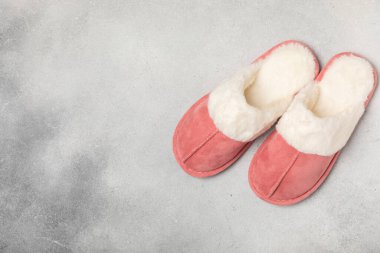 Açık renkli arka planda yumuşak terlikler, yakın plan. Ev terlikleri. Ev için rahat ayakkabılar. Ayak bakımı konsepti. Ev rahatlığı. Mesaj için yer var. Boşluğu kopyala.