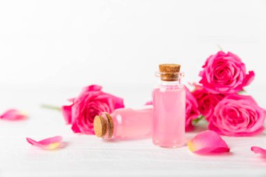 Arka planda gül yağı. Güller ve bir şişe parfümlü su. Romaterapi tedavisi. Güzellik konsepti. Spa prosedürü. Doğal organik yağ. Stres önleyici, detoks gevşetici.