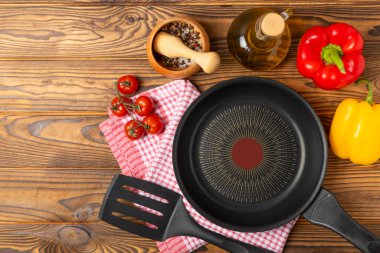 Kızartma tavası. Boş kızartma tavası ve mutfak aletleri ahşap dokulu arka planda. Yemek konsepti. Üst Manzara. Mesaj için yer var. Düz yatıyordu. Tarif.