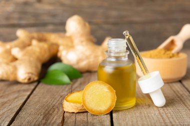 Doku arka planında zencefil yağı var. Taze zencefil dilimleri. Esans, serum, yağ. Alternatif tıp. Beden eğitimi. Sağlık ve güzellik konsepti. Mesaj için yer. Boşluğu kopyala.