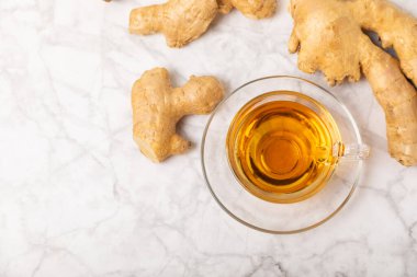 Tahta zemin üzerinde zencefil kökü dilimleri olan bir fincan sıcak zencefil çayı. Isıtıcı içecek. Alternatif tıp. Ballı, limonlu, zencefilli ve naneli çay. Mesaj için yer var. Boşluğu kopyala