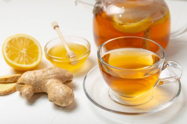 Tahta zemin üzerinde zencefil kökü dilimleri olan bir fincan sıcak zencefil çayı. Isıtıcı içecek. Alternatif tıp. Ballı, limonlu, zencefilli ve naneli çay. Mesaj için yer var. Boşluğu kopyala