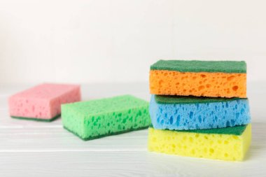 Arka planda renkli bulaşık süngerleri. Mutfak süngeri. Temizlik konsepti, temizlik hizmeti. Bulaşık deterjanı ve temiz ve kirli tabaklar. Metin için yer, kopyalama alanı. Bulaşıkları yıka..