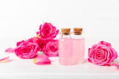 Arka planda gül yağı. Güller ve bir şişe parfümlü su. Romaterapi tedavisi. Güzellik konsepti. Spa prosedürü. Doğal organik yağ. Stres önleyici, detoks gevşetici.