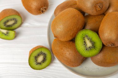 Ahşap arka planda Kivi. Masada tam meyve ve dilimler halinde yeşil kivi var. Taze sulu kivi. Tropik meyve. Organik meyve. Sağlıklı beslenme. Mesaj için yer var. Boşluğu kopyala.