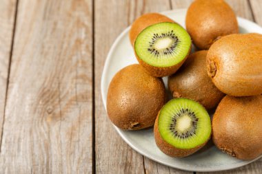 Ahşap arka planda Kivi. Masada tam meyve ve dilimler halinde yeşil kivi var. Taze sulu kivi. Tropik meyve. Organik meyve. Sağlıklı beslenme. Mesaj için yer var. Boşluğu kopyala.