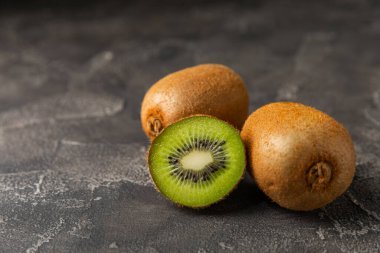 Ahşap arka planda Kivi. Masada tam meyve ve dilimler halinde yeşil kivi var. Taze sulu kivi. Tropik meyve. Organik meyve. Sağlıklı beslenme. Mesaj için yer var. Boşluğu kopyala.