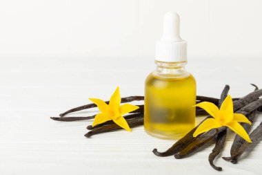 Bir şişe vanilya yağı ve desenli arka planda vanilya çiçeği. aromatik vanilyalı fasulye. Vanilya özü. Spa konsepti. Güzellik ve özen. Mesaj için yer. Boşluğu kopyala.