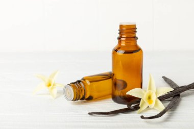 Bir şişe vanilya yağı ve desenli arka planda vanilya çiçeği. aromatik vanilyalı fasulye. Vanilya özü. Spa konsepti. Güzellik ve özen. Mesaj için yer. Boşluğu kopyala.