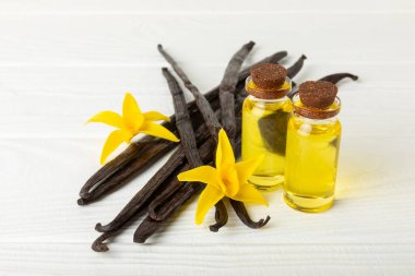 Bir şişe vanilya yağı ve desenli arka planda vanilya çiçeği. aromatik vanilyalı fasulye. Vanilya özü. Spa konsepti. Güzellik ve özen. Mesaj için yer. Boşluğu kopyala.