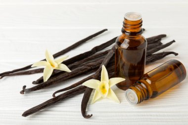 Bir şişe vanilya yağı ve desenli arka planda vanilya çiçeği. aromatik vanilyalı fasulye. Vanilya özü. Spa konsepti. Güzellik ve özen. Mesaj için yer. Boşluğu kopyala.