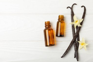 Bir şişe vanilya yağı ve desenli arka planda vanilya çiçeği. aromatik vanilyalı fasulye. Vanilya özü. Spa konsepti. Güzellik ve özen. Mesaj için yer. Boşluğu kopyala.