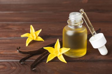 Bir şişe vanilya yağı ve desenli arka planda vanilya çiçeği. aromatik vanilyalı fasulye. Vanilya özü. Spa konsepti. Güzellik ve özen. Mesaj için yer. Boşluğu kopyala.