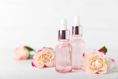 Arka planda gül yağı. Güller ve bir şişe parfümlü su. Romaterapi tedavisi. Güzellik konsepti. Spa prosedürü. Doğal organik yağ. Stres önleyici, detoks gevşetici.