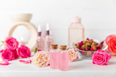 Arka planda gül yağı. Güller ve bir şişe parfümlü su. Romaterapi tedavisi. Güzellik konsepti. Spa prosedürü. Doğal organik yağ. Stres önleyici, detoks gevşetici.