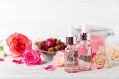 Arka planda gül yağı. Güller ve bir şişe parfümlü su. Romaterapi tedavisi. Güzellik konsepti. Spa prosedürü. Doğal organik yağ. Stres önleyici, detoks gevşetici.