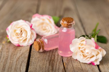 Arka planda gül yağı. Güller ve bir şişe parfümlü su. Romaterapi tedavisi. Güzellik konsepti. Spa prosedürü. Doğal organik yağ. Stres önleyici, detoks gevşetici.