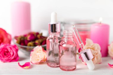 Arka planda gül yağı. Güller ve bir şişe parfümlü su. Romaterapi tedavisi. Güzellik konsepti. Spa prosedürü. Doğal organik yağ. Stres önleyici, detoks gevşetici.