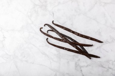 Dokulu bir arka planda vanilya kabukları. Vanilya çiçekleri ve tohumlar. Vanilyalı fasulye. Hamur işleri ve tatlılar için baharatlı baharat. Baharat. Mesaj için yer var. Boşluğu Kopyala