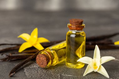 Bir şişe vanilya yağı ve desenli arka planda vanilya çiçeği. aromatik vanilyalı fasulye. Vanilya özü. Spa konsepti. Güzellik ve özen. Mesaj için yer. Boşluğu kopyala.