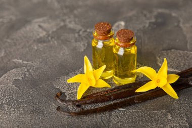 Bir şişe vanilya yağı ve desenli arka planda vanilya çiçeği. aromatik vanilyalı fasulye. Vanilya özü. Spa konsepti. Güzellik ve özen. Mesaj için yer. Boşluğu kopyala.