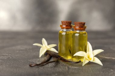 Bir şişe vanilya yağı ve desenli arka planda vanilya çiçeği. aromatik vanilyalı fasulye. Vanilya özü. Spa konsepti. Güzellik ve özen. Mesaj için yer. Boşluğu kopyala.