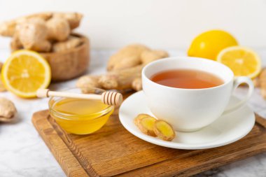 Tahta zemin üzerinde zencefil kökü dilimleri olan bir fincan sıcak zencefil çayı. Isıtıcı içecek. Alternatif tıp. Ballı, limonlu, zencefilli ve naneli çay. Mesaj için yer var. Boşluğu kopyala