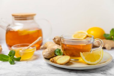 Tahta zemin üzerinde zencefil kökü dilimleri olan bir fincan sıcak zencefil çayı. Isıtıcı içecek. Alternatif tıp. Ballı, limonlu, zencefilli ve naneli çay. Mesaj için yer var. Boşluğu kopyala