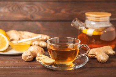 Tahta zemin üzerinde zencefil kökü dilimleri olan bir fincan sıcak zencefil çayı. Isıtıcı içecek. Alternatif tıp. Ballı, limonlu, zencefilli ve naneli çay. Mesaj için yer var. Boşluğu kopyala