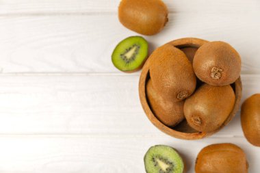 Ahşap arka planda Kivi. Masada tam meyve ve dilimler halinde yeşil kivi var. Taze sulu kivi. Tropik meyve. Organik meyve. Sağlıklı beslenme. Mesaj için yer var. Boşluğu kopyala.